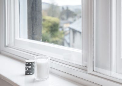 Glass of milk on window board of house window installed with Granada secondary glazing sliding unit in white